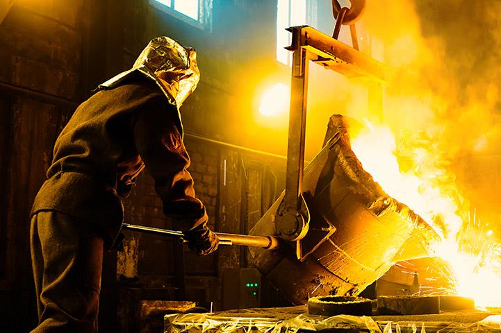 worker pouring molten metal into crucibles