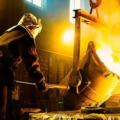 worker pouring molten metal into crucibles