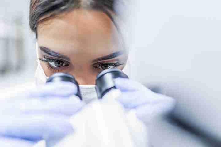 employee looking into microscope