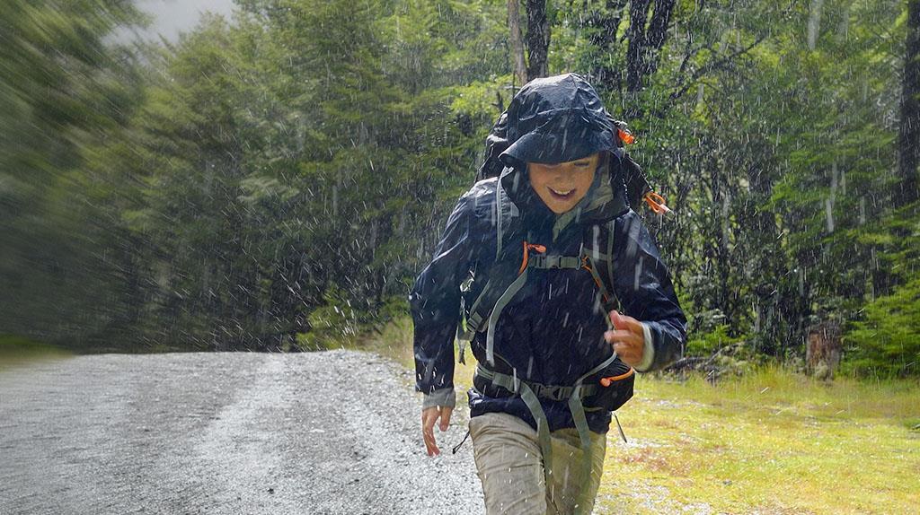 person running in forest wearing blue rain coat