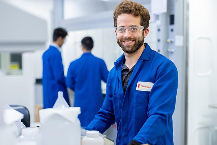 Employee in safety glasses and Chemours uniform shirt
