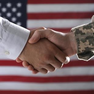 Two hands shaking in front of an American Flag
