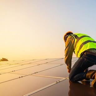 Man kneeling on top of solar panels