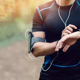 man in black running attire and wearing arm band with smartphone checking watch
