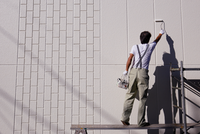 Man on scaffolding painting a wall