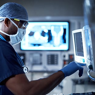 An image of a physician looking at a medical device in a hospital room.