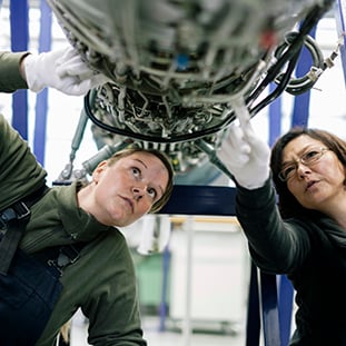 An image of two service technicians fixing an airplane.