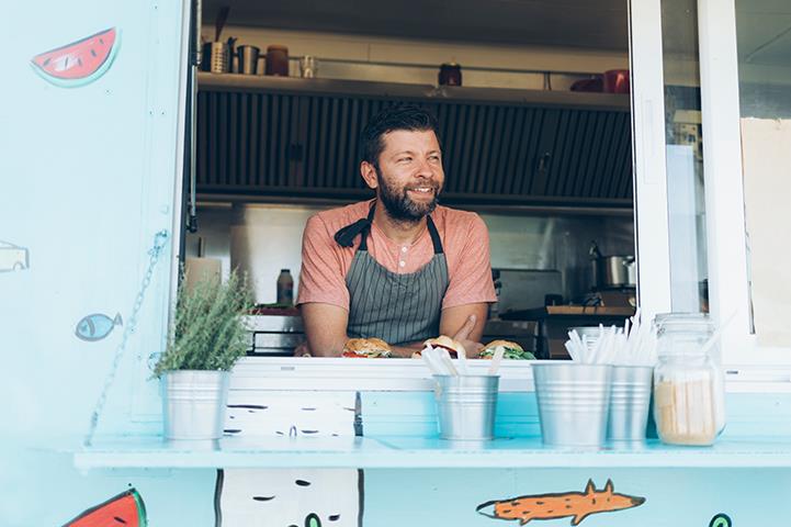 smiling man leaning out of open window of colorful food truck