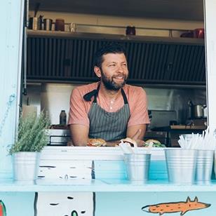 smiling man leaning out of open window of colorful food truck