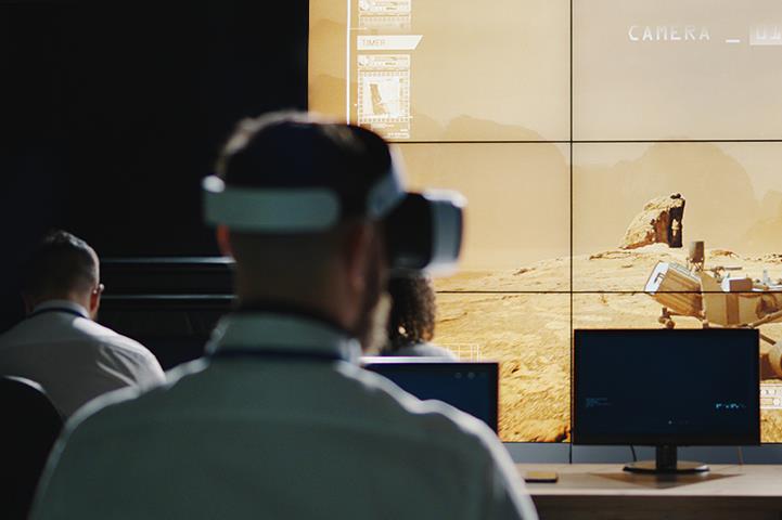 three scientists looking at screen projecting mars rover