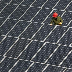 worker in red hardhat checking out solar panels