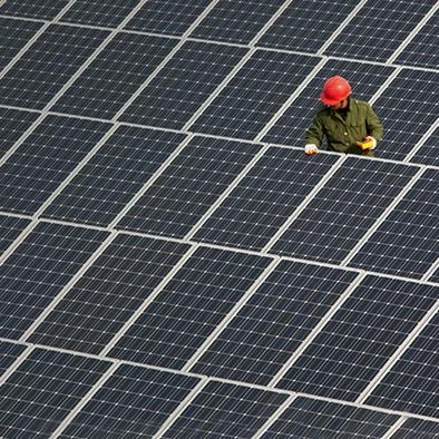 worker in red hardhat checking out solar panels