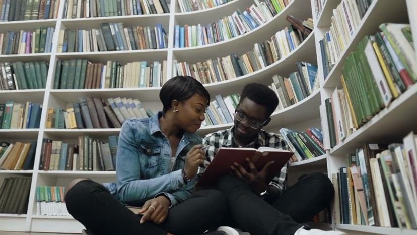 Two Black students studying in a library together. 
