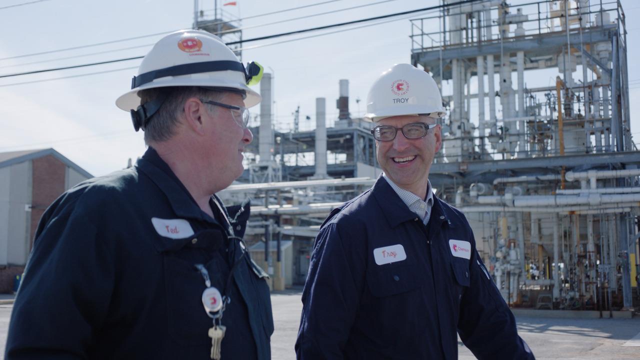 two employees standing outside of a facility