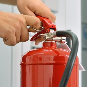 person removing pin from a red fire extinguisher