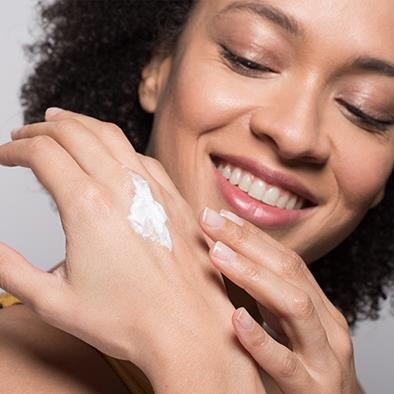 smiling woman putting lotion on her hand