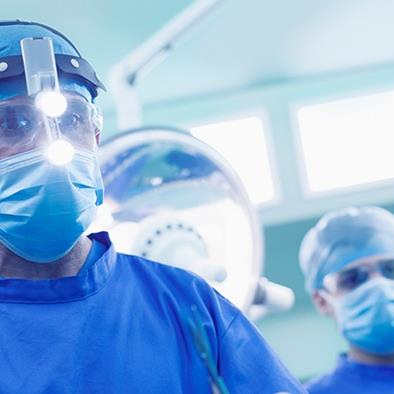 surgeon in blue wearing headlamp in operating room