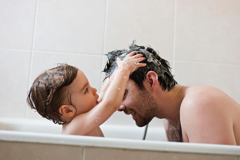 toddler washing fathers hair in the bathtub