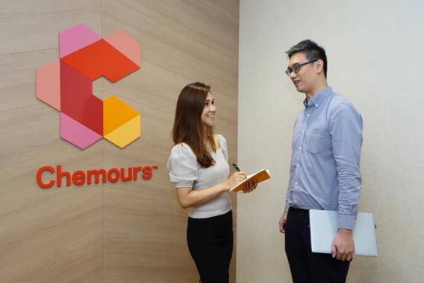 Two employees talking in front of a Chemours logo