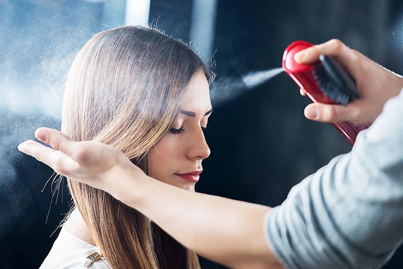 woman at salon having hair sprayed with product