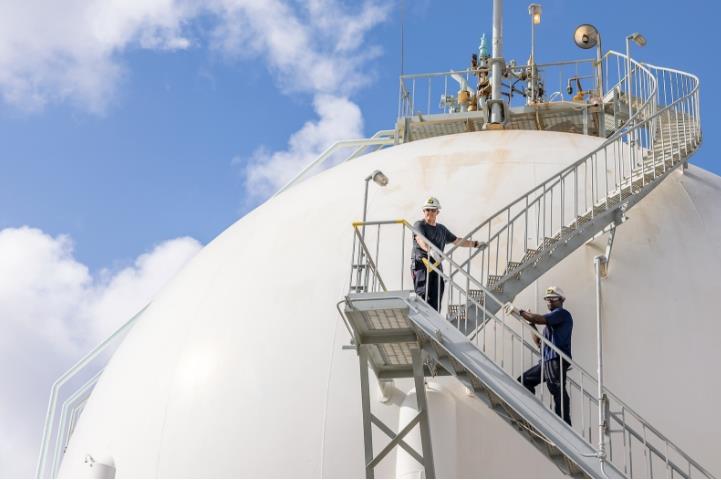 Two employees climbing staircase to top of a round storage container