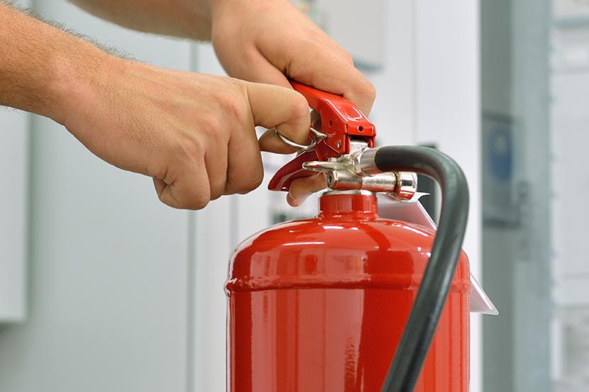 person removing pin from a red fire extinguisher 
