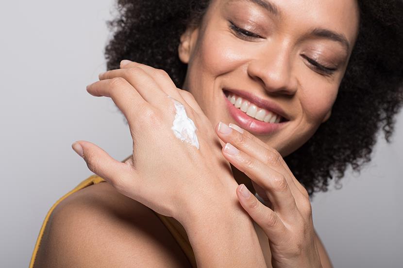 smiling woman putting lotion on her hand