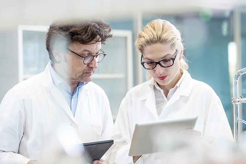 man and woman in white lab coats looking at tablets