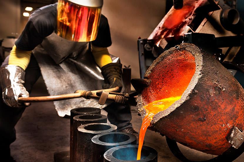 worker pouring molten steel into crucibles in a foundry