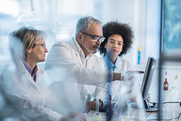 An image of three chemists analyzing research data.