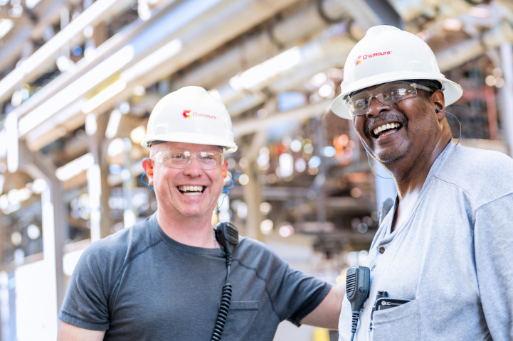 two men wearing chemours hardhats at a factory