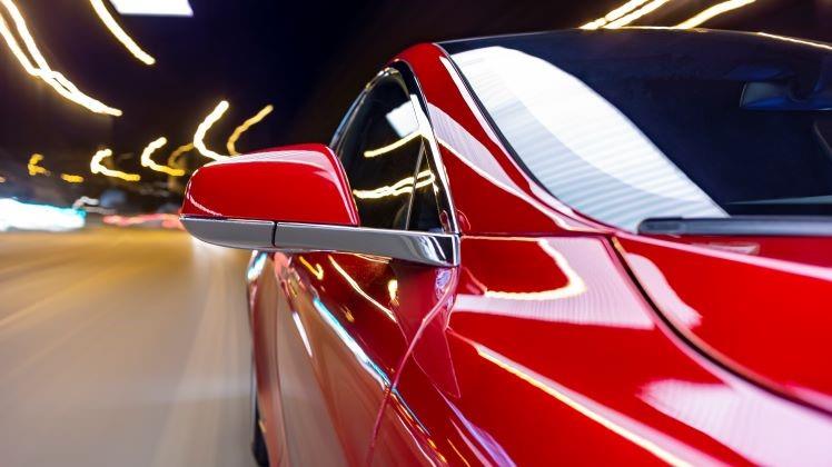 red car driving fast along road