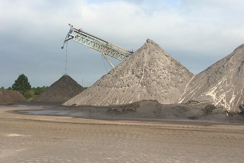 large mining equipment crane behind large piles of ilmenite staurolite zircon or zircore minerals