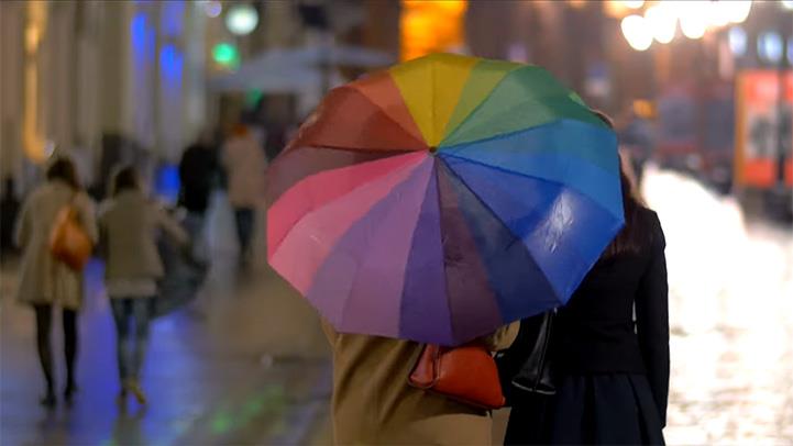 Multi-colored umbrella over people walking in the rain